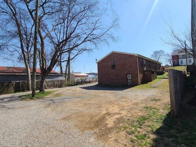 view of home's exterior with fence, brick siding, and driveway