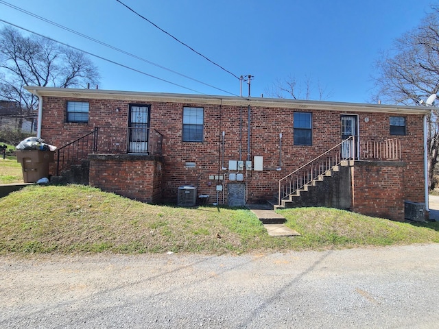 exterior space featuring a lawn, brick siding, and central AC