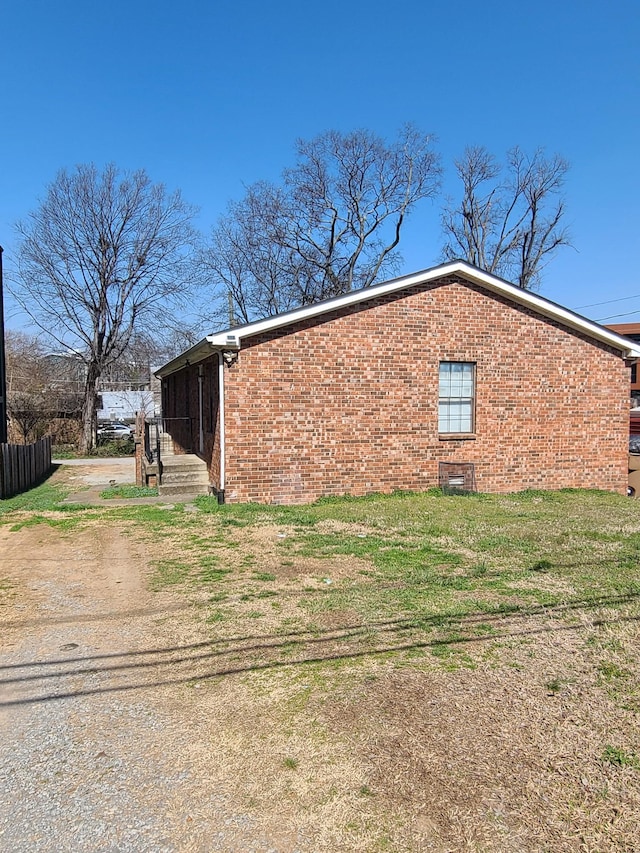 view of home's exterior featuring brick siding, a lawn, and fence