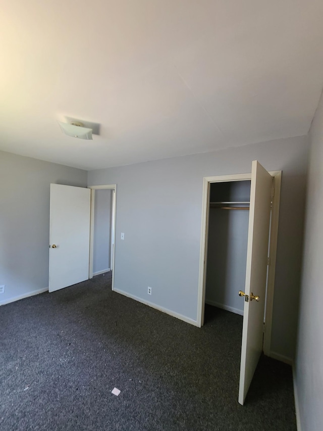 unfurnished bedroom featuring a closet, dark carpet, and baseboards