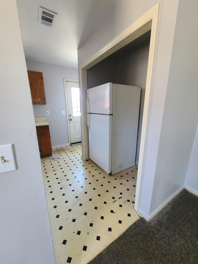 kitchen with visible vents, brown cabinets, freestanding refrigerator, and baseboards