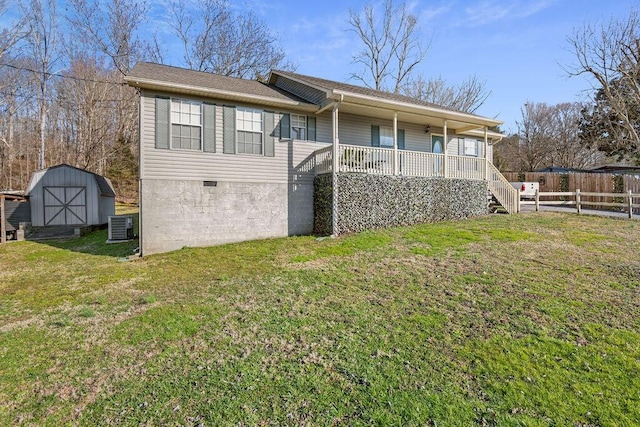 rear view of property with cooling unit, a shed, an outdoor structure, crawl space, and a lawn