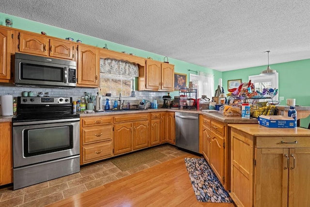 kitchen with a sink, stainless steel appliances, a peninsula, and light countertops