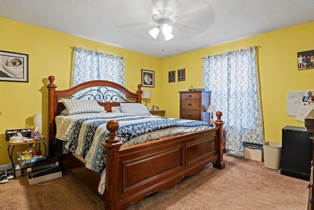 bedroom featuring a textured ceiling, a ceiling fan, and light carpet