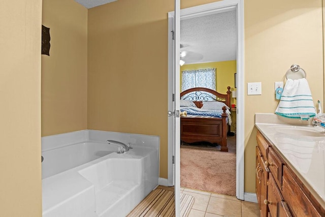 ensuite bathroom with tile patterned flooring, connected bathroom, vanity, a bath, and a textured ceiling