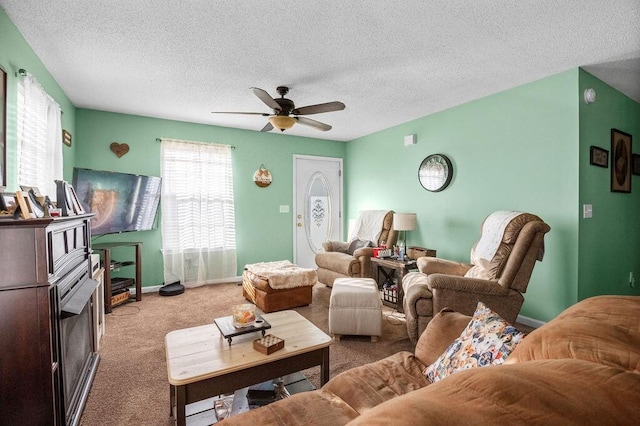 living area featuring baseboards, carpet, ceiling fan, and a textured ceiling