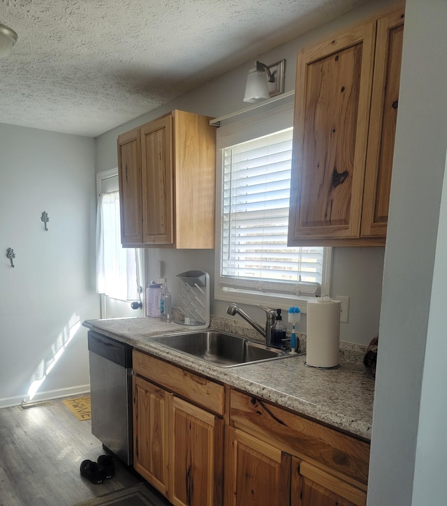 kitchen featuring wood finished floors, a sink, light countertops, a textured ceiling, and dishwasher