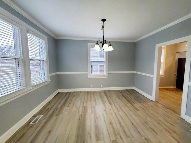 unfurnished dining area with visible vents, light wood-style flooring, baseboards, and ornamental molding