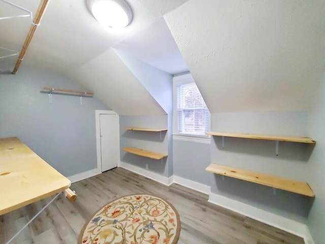 interior space featuring baseboards, lofted ceiling, and wood finished floors