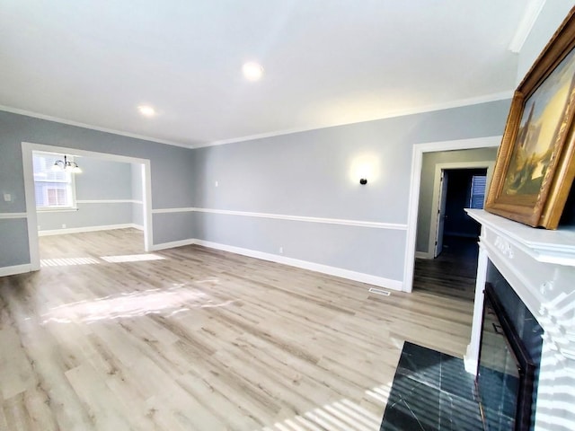 unfurnished living room with a fireplace, crown molding, light wood-style floors, and baseboards