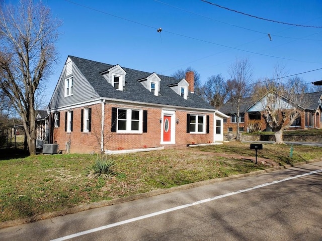 view of front of house featuring a front lawn, central AC unit, and brick siding