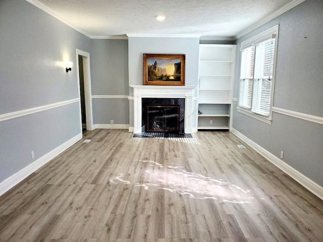 unfurnished living room with a premium fireplace, baseboards, wood finished floors, and crown molding