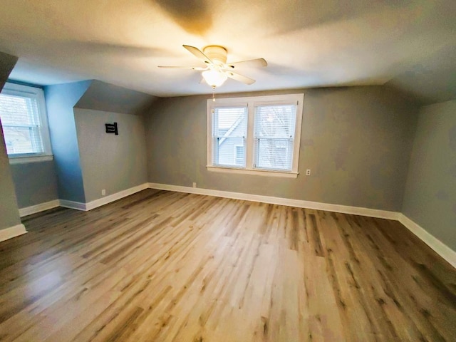 bonus room with a wealth of natural light, vaulted ceiling, baseboards, and wood finished floors