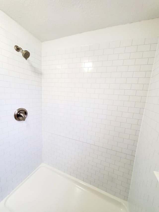 bathroom with a tile shower and a textured ceiling