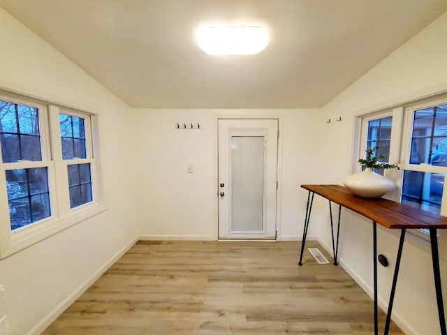 entrance foyer featuring baseboards, light wood finished floors, and vaulted ceiling