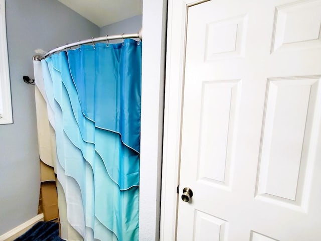 bathroom featuring curtained shower and baseboards