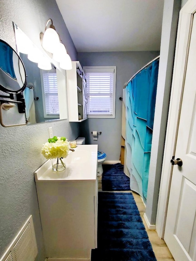 bathroom with visible vents, a healthy amount of sunlight, vanity, and toilet