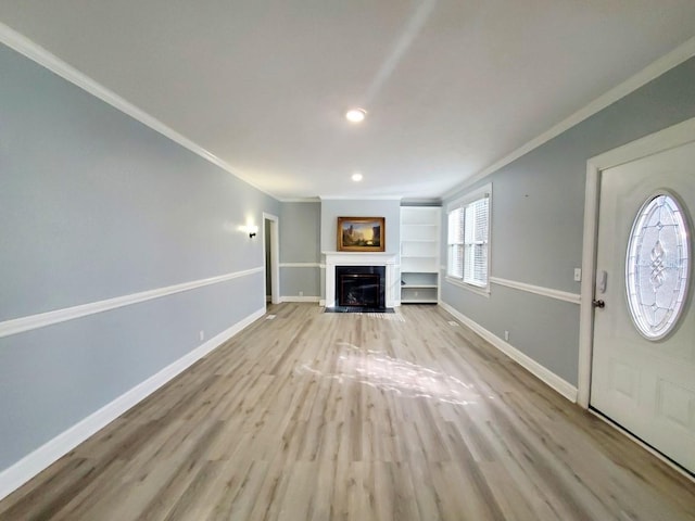 unfurnished living room featuring a fireplace with flush hearth, light wood-type flooring, baseboards, and ornamental molding