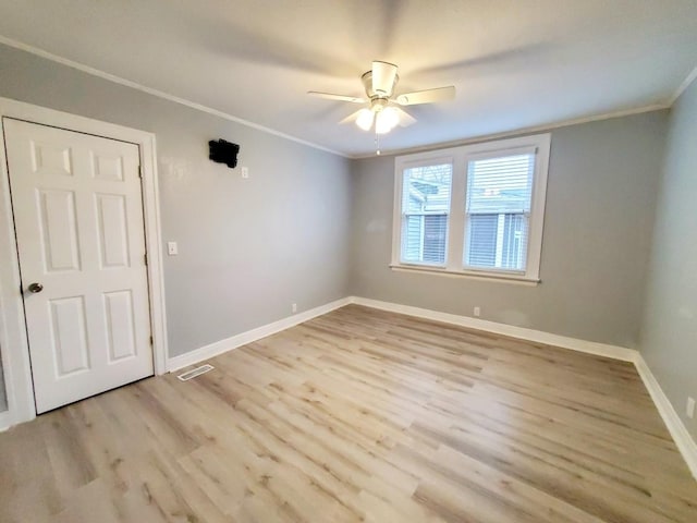 spare room with visible vents, ceiling fan, baseboards, ornamental molding, and wood finished floors