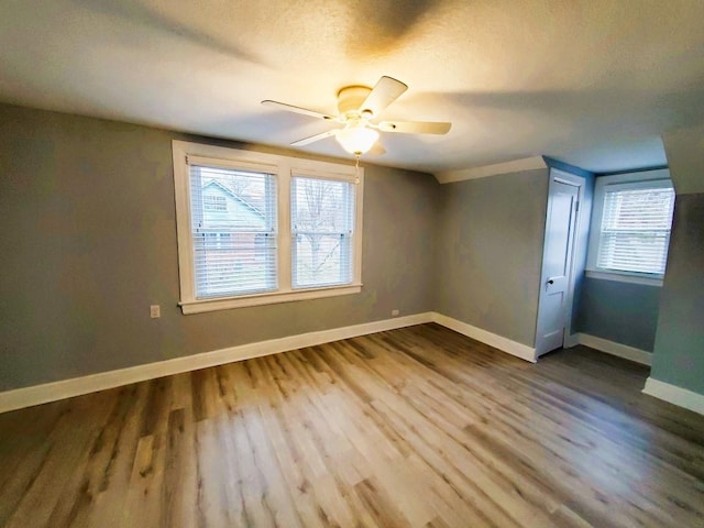 interior space with a textured ceiling, a ceiling fan, baseboards, and wood finished floors