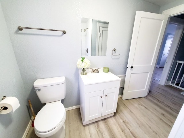 bathroom featuring vanity, toilet, wood finished floors, and baseboards