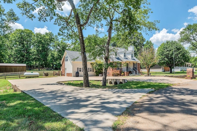 view of front of house with brick siding, driveway, a front yard, and fence