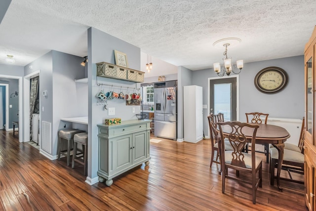 dining room with baseboards, wood-type flooring, a textured ceiling, and a chandelier