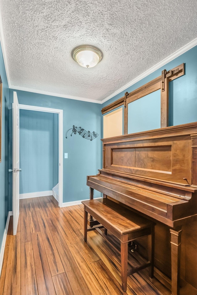 sitting room featuring crown molding, wood finished floors, baseboards, and a textured ceiling