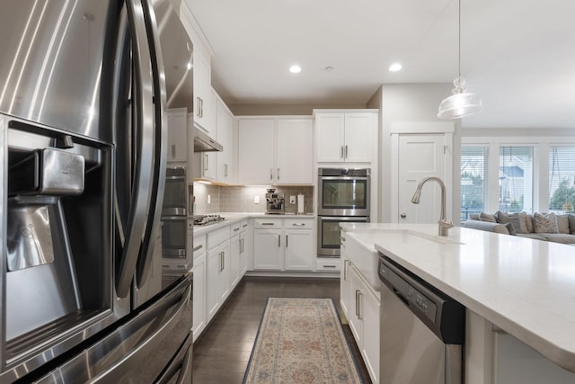 kitchen with decorative backsplash, white cabinets, and stainless steel appliances