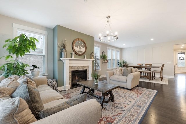 living room featuring plenty of natural light, baseboards, dark wood-type flooring, and an inviting chandelier