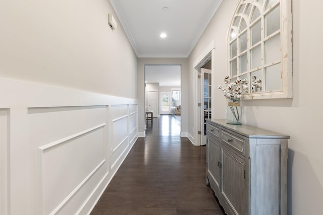 corridor featuring dark wood finished floors, recessed lighting, a decorative wall, wainscoting, and crown molding