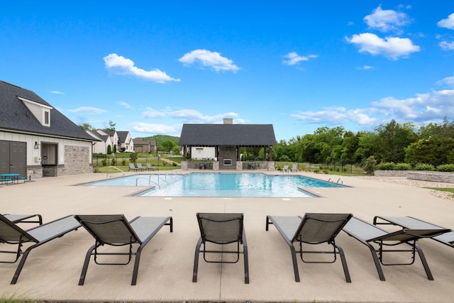 pool with a patio, an outbuilding, and fence