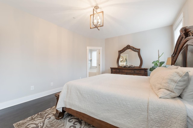 bedroom featuring a notable chandelier, dark wood-type flooring, and baseboards