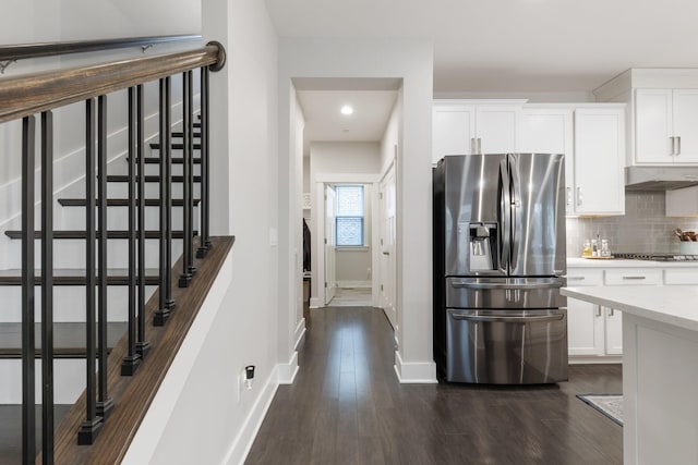 kitchen with dark wood finished floors, under cabinet range hood, appliances with stainless steel finishes, and decorative backsplash