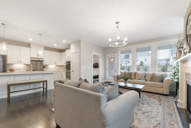 living room featuring dark wood finished floors, recessed lighting, a fireplace, and an inviting chandelier