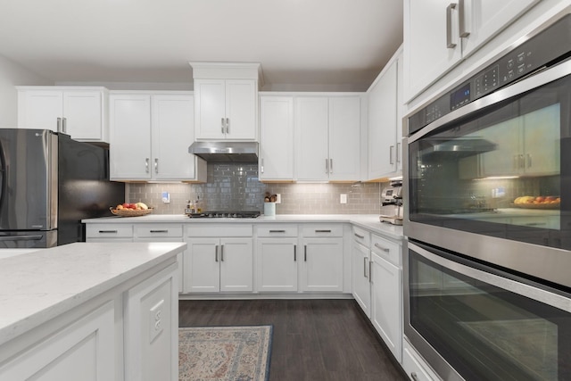 kitchen featuring decorative backsplash, white cabinets, and appliances with stainless steel finishes