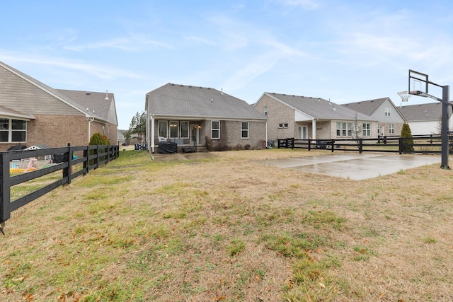 back of property with a patio area, basketball hoop, a yard, and fence