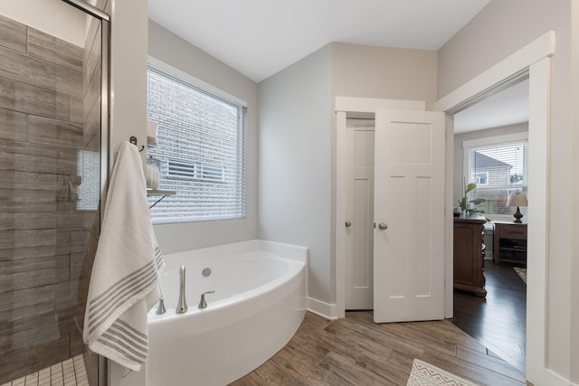 bathroom with a bath, wood finished floors, and a stall shower