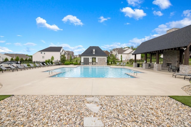 pool with a patio area, a residential view, an outdoor structure, and fence