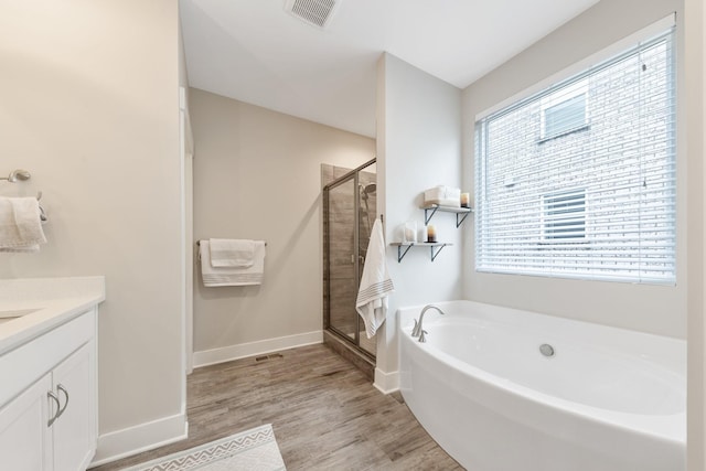 bathroom featuring visible vents, a shower stall, wood finished floors, a bath, and vanity