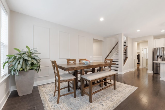 dining area with dark wood-type flooring, recessed lighting, stairway, a decorative wall, and baseboards