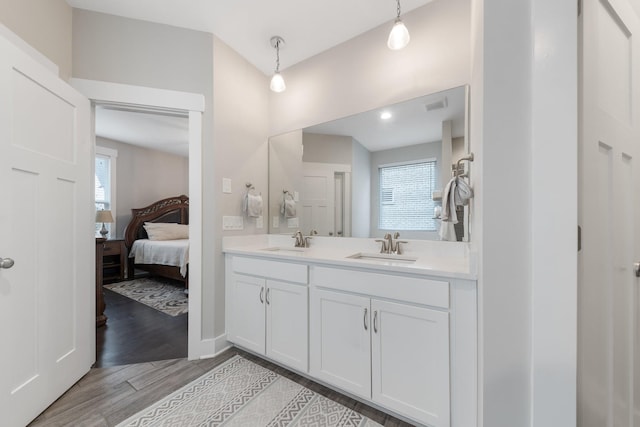 ensuite bathroom featuring a sink, connected bathroom, visible vents, and wood finished floors