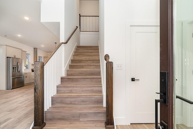 staircase with recessed lighting and wood finished floors