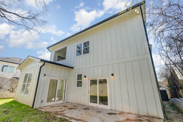 rear view of house with board and batten siding and a patio area