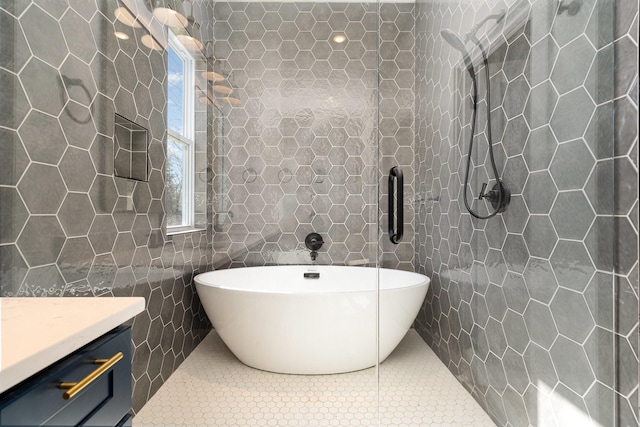 full bath featuring a freestanding tub, a tile shower, tile walls, tile patterned flooring, and vanity