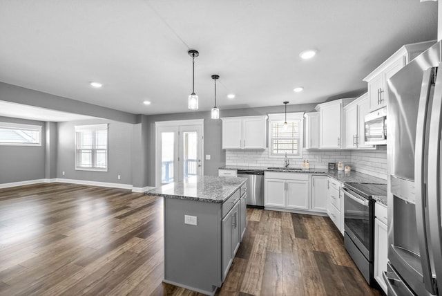 kitchen with a sink, tasteful backsplash, a kitchen island, dark wood-style floors, and stainless steel appliances