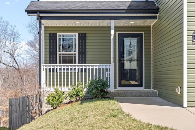 entrance to property featuring fence, covered porch, and a shingled roof