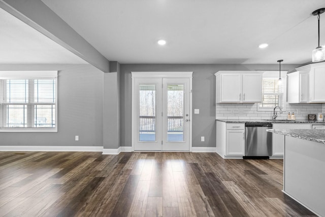 kitchen with light stone countertops, stainless steel dishwasher, dark wood-style floors, and tasteful backsplash