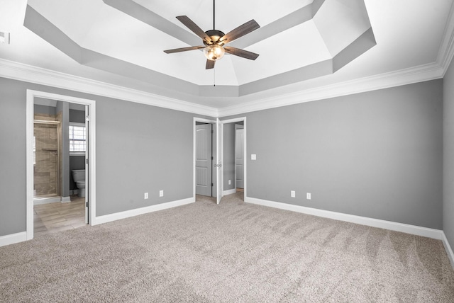 unfurnished bedroom with a tray ceiling, baseboards, and carpet