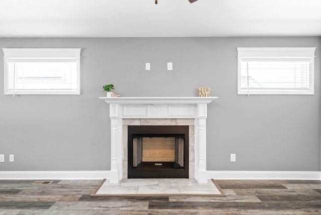 interior details featuring visible vents, a tile fireplace, baseboards, and wood finished floors